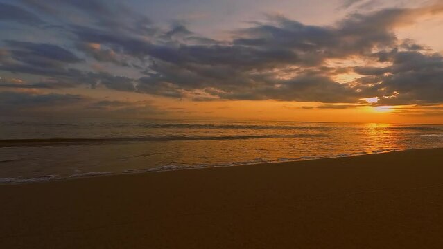 Golden sky clouds sunrise in morning at Samila beach, Songkhla, Thailand. Dramatic sea sunrise. Burning sky and shining golden small waves.
