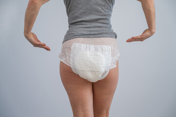 Rear view of a woman pointing at adult diapers. Incontinence problem. 