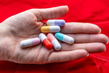 woman holds a lot of colored pill capsules in her palms