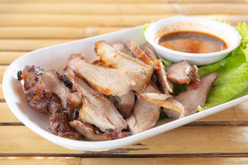 Thai grilled pork neck on plate with dipping sauce