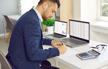 Plakat Tax consultant. Man working in modern office, counting financial data. Stock exchange information on computer screens on table. Calculation of cost of loan for company.