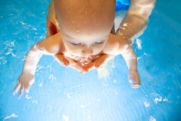 Adorable baby girl enjoying swimming in a pool with her mother early development class for infants teaching children to swim and dive.