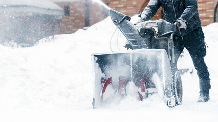 a janitor on a snowplow removes snow in the courtyard of a residential building