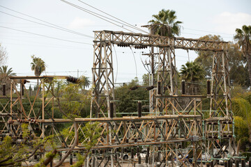 Daytime view of old, rusted crumbling electrical substation infrastructure.