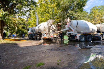 Concrete mixer at the construction site, pouring concrete from one mixer to other with pump for...