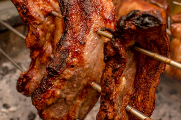 Several pieces of Liempo, or pork belly skewered on a spit and roasted on an oven at a roadside restaurant.
