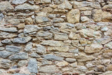 Stones of different shapes and sizes are built into the wall
