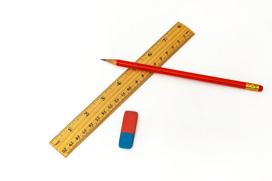 On a white background lie a ruler, an eraser and a simple pencil