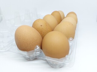 Close up dozen brown free range hen eggs on plastic container isolated on white background side view 