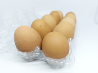 Close up dozen brown free range hen eggs on plastic container isolated on white background side view 