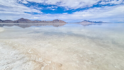 Panoramic view of the white salt beach at lake of Bonneville Salt Flats, Wendover, Western Utah, USA, America. Beautiful mountain reflections. Looking at summits of Silver Island Mountain range