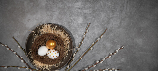 HAPPY EASTER holiday celebration backgroud greeting card - Easter nests with gold painted easter eggs and catkins on concrete table texture, top view