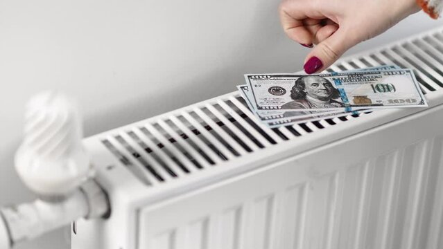Expensive gas heat high heating cost price increase female hands put dollar on thermostat radiator