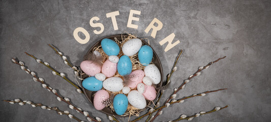 Frohe Ostern Feier Feiertage Hintergrund mit deutschem Text - Osternester mit Wachtel Ostereiern und Palmkätzchen auf Tisch mit Beton Textur, Draufsicht