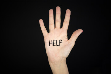 Hand stop sign with word HELP written to campaign against gender violence and pain. Hand raised to dissuade for self harm awareness, stop abusing, bullying, mental health. Copy space.