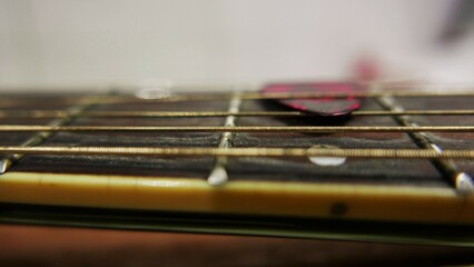 A close-up of rusty guitar strings. A pick on a guitar neck. Details of an old acoustic guitar. A...