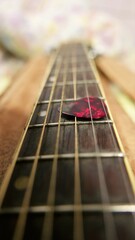 A guitar pick on a guitar neck. A guitar pick, close-up shot. A guitar neck, close-up view. Playing...