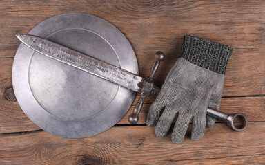 Knight armor, sword and shield on wooden background