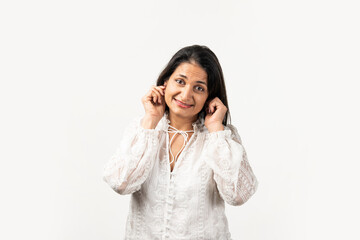 Mid aged Indian woman in a sorry pose, holding both ears. Standing isolated over white background.