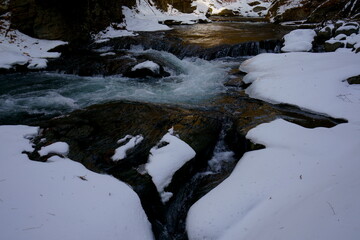 冬の雪のある山の中の流れ