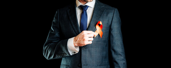 Aid ribbon silk. Red ribbon in hiv world day in man hand. Awareness aids and cancer symbol on black background. HIV, AIDS and aging awareness month with copy space.