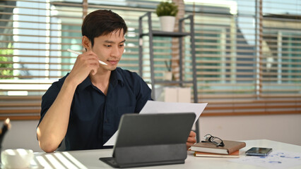 Smart businessman reading reports, working on financial and marketing project at modern home office