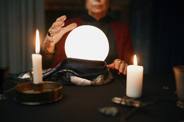 Confident fortune teller doing predictions with illuminated crystal ball