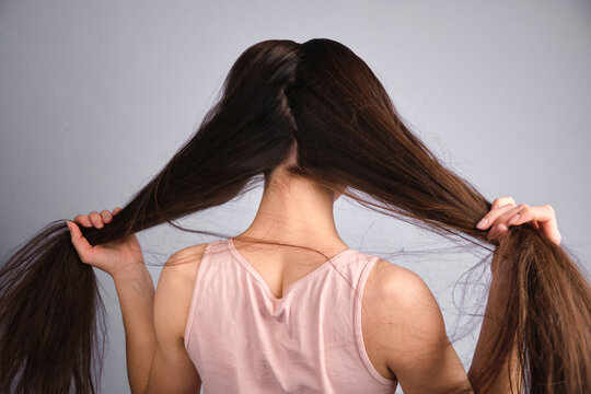 Rear View Woman Holding Long Straight Thin Hair In Hand Strand Of Her Long Silky Hair After Shower Bath