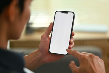 Close up view of man holding and typing text message on mobile phone. Empty screen for your advertise design