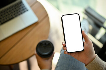 Top view of a woman using her modern smartphone and sipping coffee while chilling in the cafe