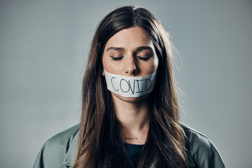 Woman, tape and mouth with silence for protest, social activism and fight against covid 19 by background. Human rights, gen z girl and studio with healthcare opinion for freedom, choice and vision