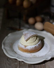 Semla on a white porcelain dish with plenty of icing sugar on top