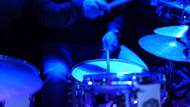 Video of a man playing the drums during a concert, no faces are shown, close up