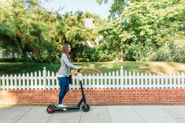 Woman Rides Scoot on Sidewalk