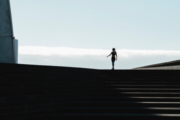 Silhouette of woman walking on stairs with blue sky in background