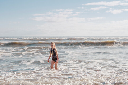 Girl in a swimsuit playing in the surf at the beach