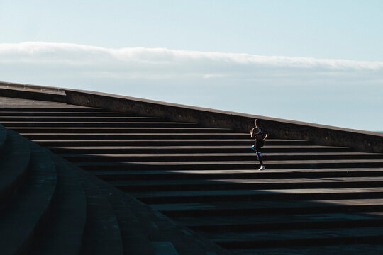Pulled back of woman running on stairs with blue sky in background