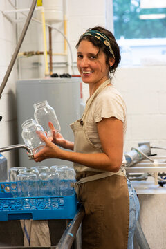 Young woman wearing headband holds two empty glass jars in kitchen