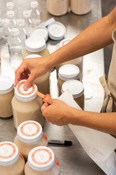 A woman affixes labels on glass jars containing pecan milk
