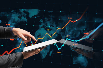 Close up of male hand pointing at cellphone with glowing business chart and map on dark background. Stock, global growth and financial graph concept. Double exposure.
