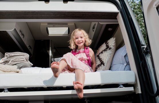 portrait of a young girl sat in bed in a camper van on vacation