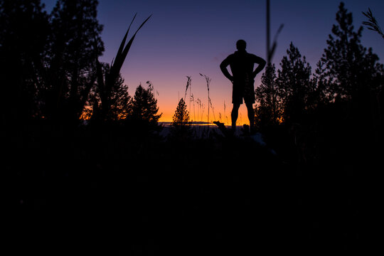 A man takes a break from a run and watches the sunset