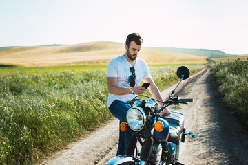 young man watches his mobile phone as he waits for the crane to bring