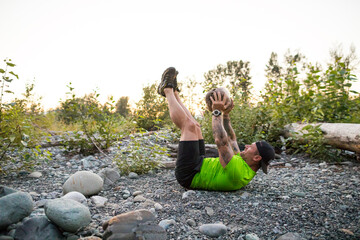 Active man integrates heavy rock into his outdoor fitness routine