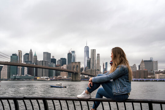 Attractive young woman watching the Brooklyn Bridge from the Hudson River in New York City