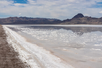 Panoramic view of beautiful mountains reflecting in lake of Bonneville Salt Flats, Wendover, Western Utah, USA, America. Looking at summits of Silver Island Mountain range. West of Great Salt Lake