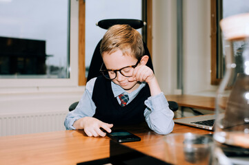 young boy looking at his dads phone whilst helping him at work