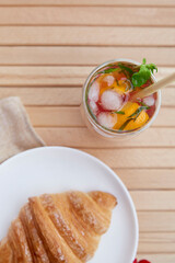  French crust croissant on the plate and refreshment strawberry mojito cocktail at the terrace. Aesthetic morning. Top view. Selective focus.