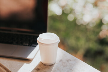 paper cup on the table workspace: laptop, tree.