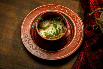Ukrainian dumplings stuffed with meat in a clay pot. Wooden table